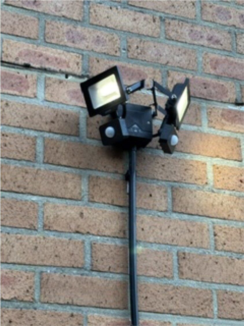 Close-up van een dubbele LED-schijnwerper met bewegingssensor op een bakstenen muur